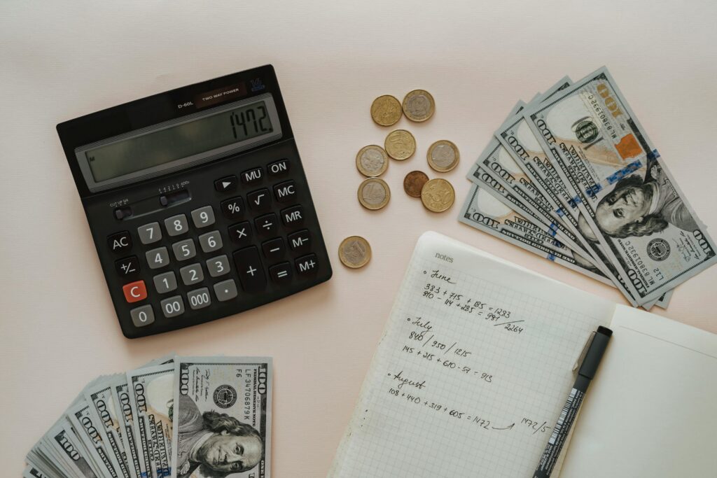 Flat lay of calculator, cash, coins, and handwritten notes for budget planning.